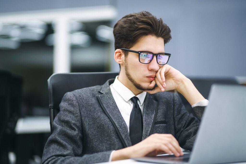 Business manager in glasses works on his laptop in the office. Freelancer working from a laptop